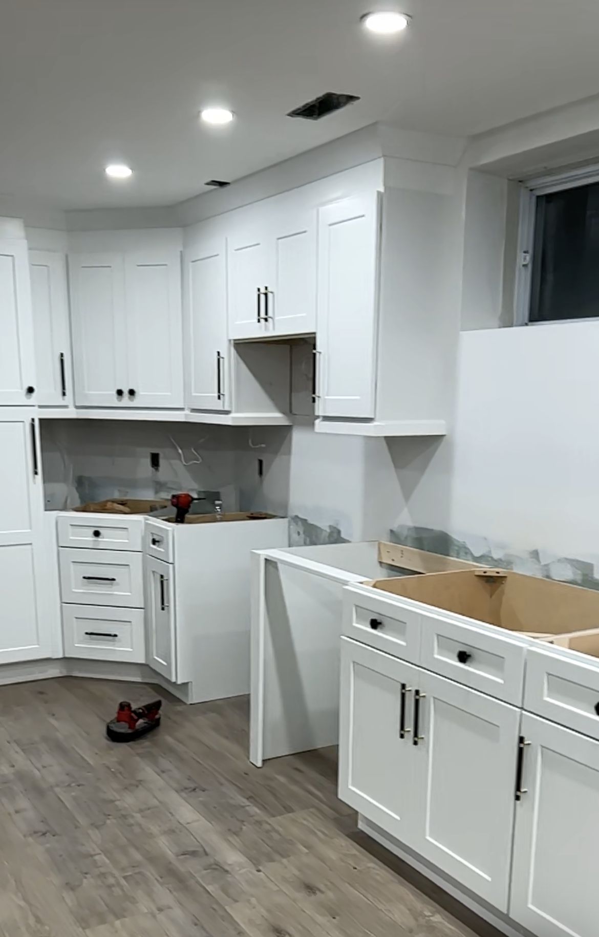 Basement kitchen with white shaker cabinets and wide-plank floors